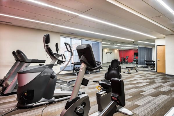 The Edge A gym room featuring various exercise equipment and a large wall of windows allowing natural light to enter.