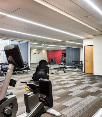 The Edge A gym room featuring various exercise equipment and a large wall of windows allowing natural light to enter.