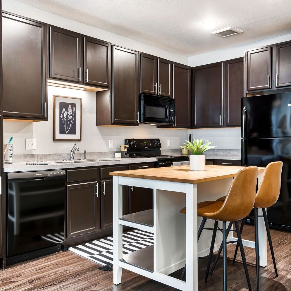 The Edge A modern kitchen featuring dark wood cabinets and sleek stainless steel appliances.