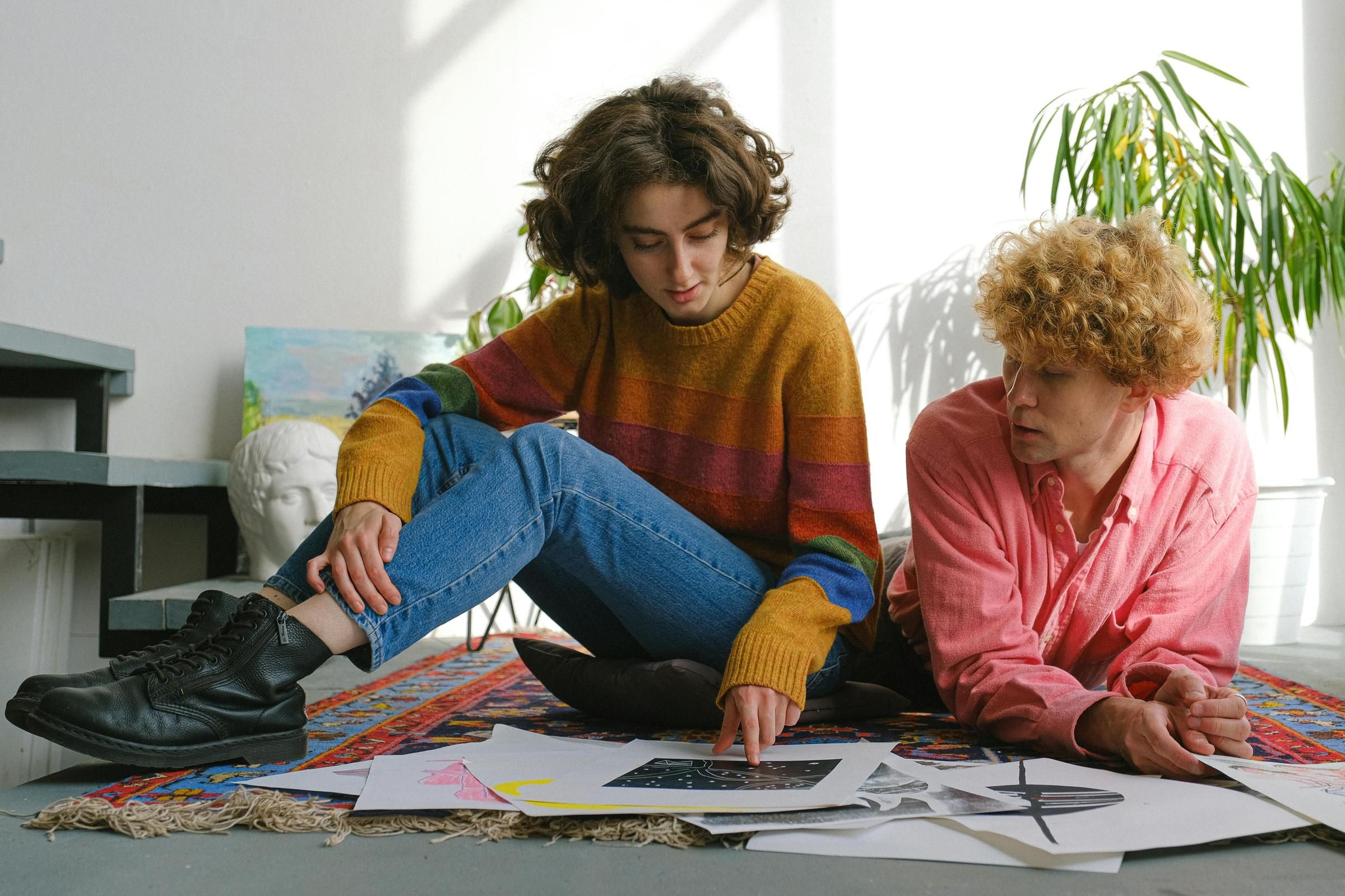The Edge Two individuals seated on the floor, surrounded by scattered papers, engaged in discussion or collaboration.
