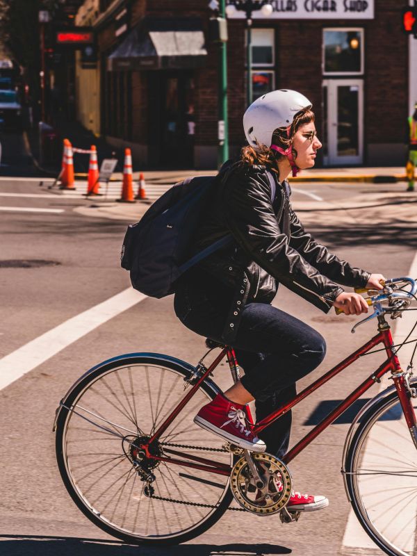 The Edge A woman riding a bicycle along a scenic path, wearing a helmet and enjoying the outdoors.